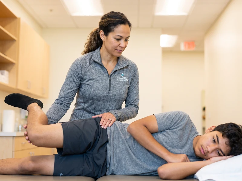 Physical therapist treating a patient’s hip while the patient lies on their side